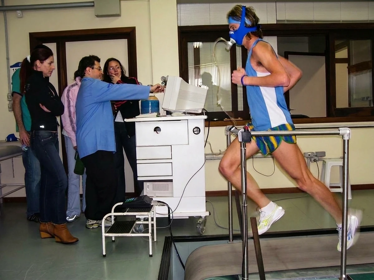 Andrigo Zaar, então atleta profissional, sendo avaliado em teste de VO₂máx na esteira, com máscara de coleta de gases e a equipe de avaliadores ao lado do analisador